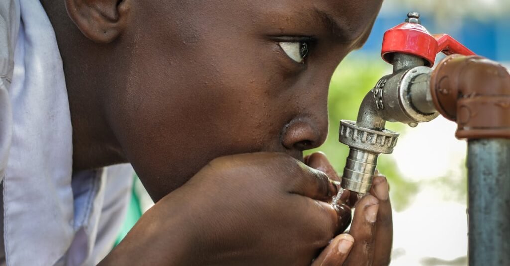 Close-up of a child drinking water from a faucet in Mwanza, Tanzania.
